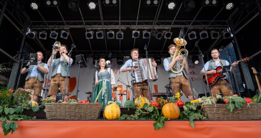 2025-09-07_EDF25_(c)ÖSF-Pöhlmann-1950 Musikgruppe in Tracht spielt auf der Bühne beim ernte.dank.festival., dekoriert mit Kürbissen, Gemüse und Erntekörben