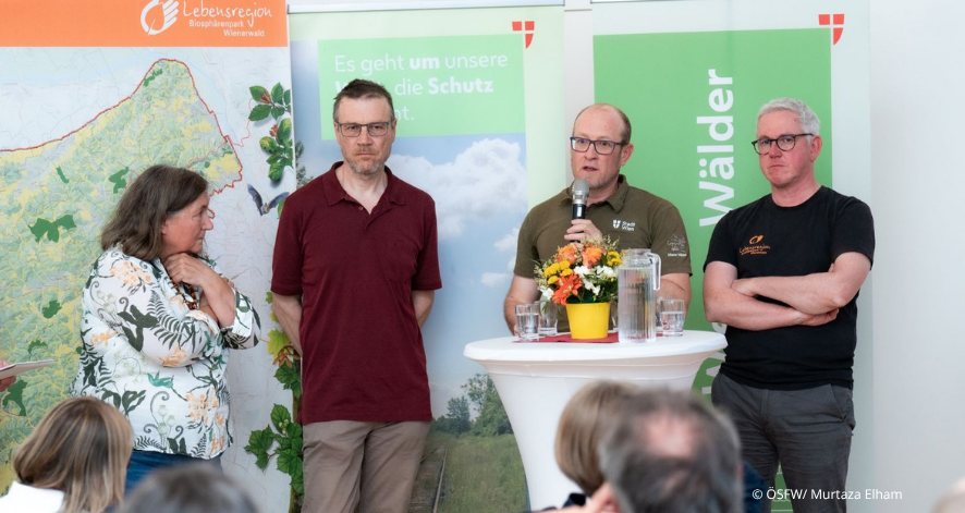 Podiumsdiskussion bei der &Ouml;kosozialen Bezirkskonferenz: Vier Personen sprechen vor Publikum &uuml;ber Natur-, Klima- und Waldschutz im Wienerwald.