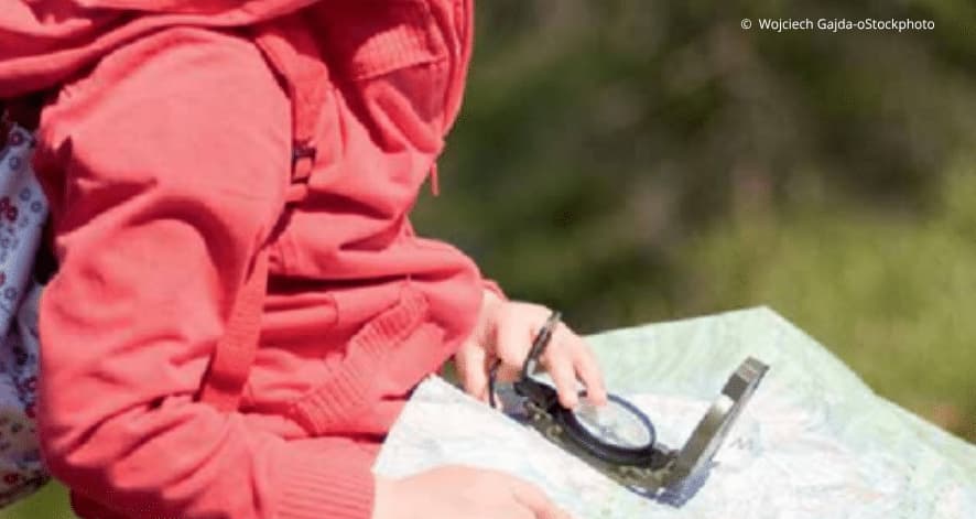 Karte und Kompass Detailaufnahme Mädchen sitzt in Wanderausrüstung, mit Kompass und Karte in der Hand
